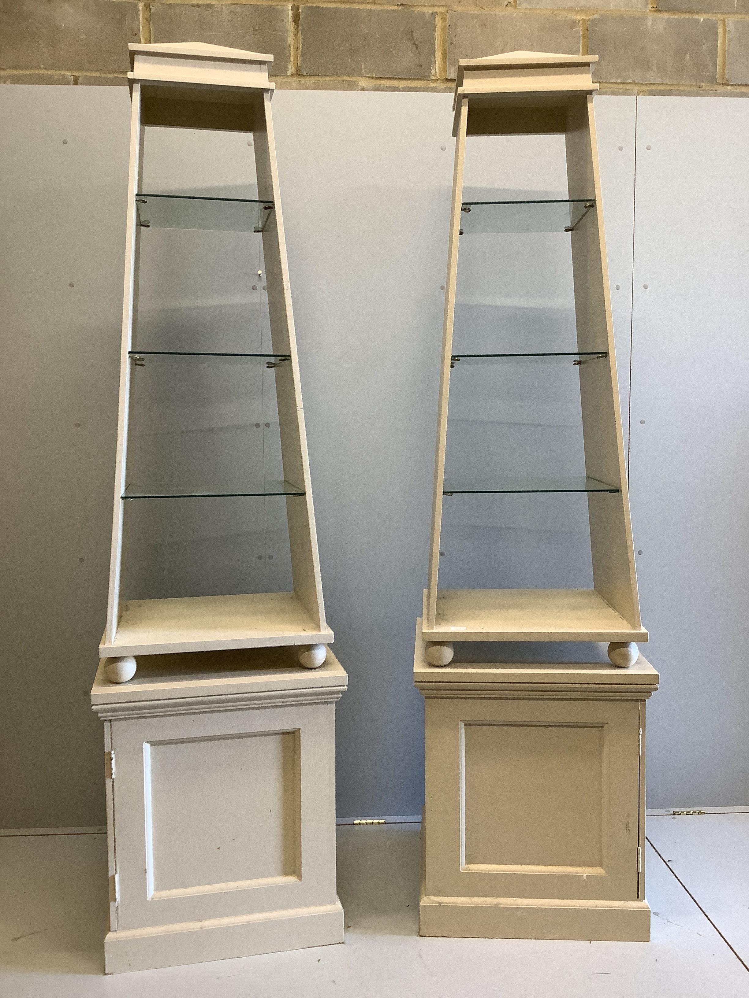 David Hicks - a pair of cream painted obelisk open shelved cabinets, on square plinths, designed by David Hicks, width 62cm, depth 62cm, height 225cm